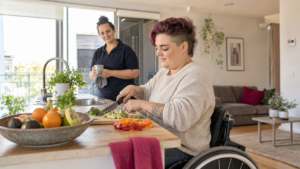 Wheelchair user preparing a meal independently with respectful support nearby